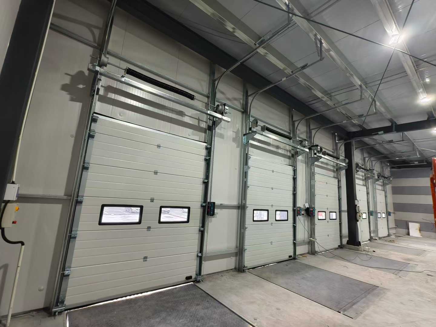 Zásilka průmyslových sekčních vrat a vyrovnávacích můstků pro skladové projekty